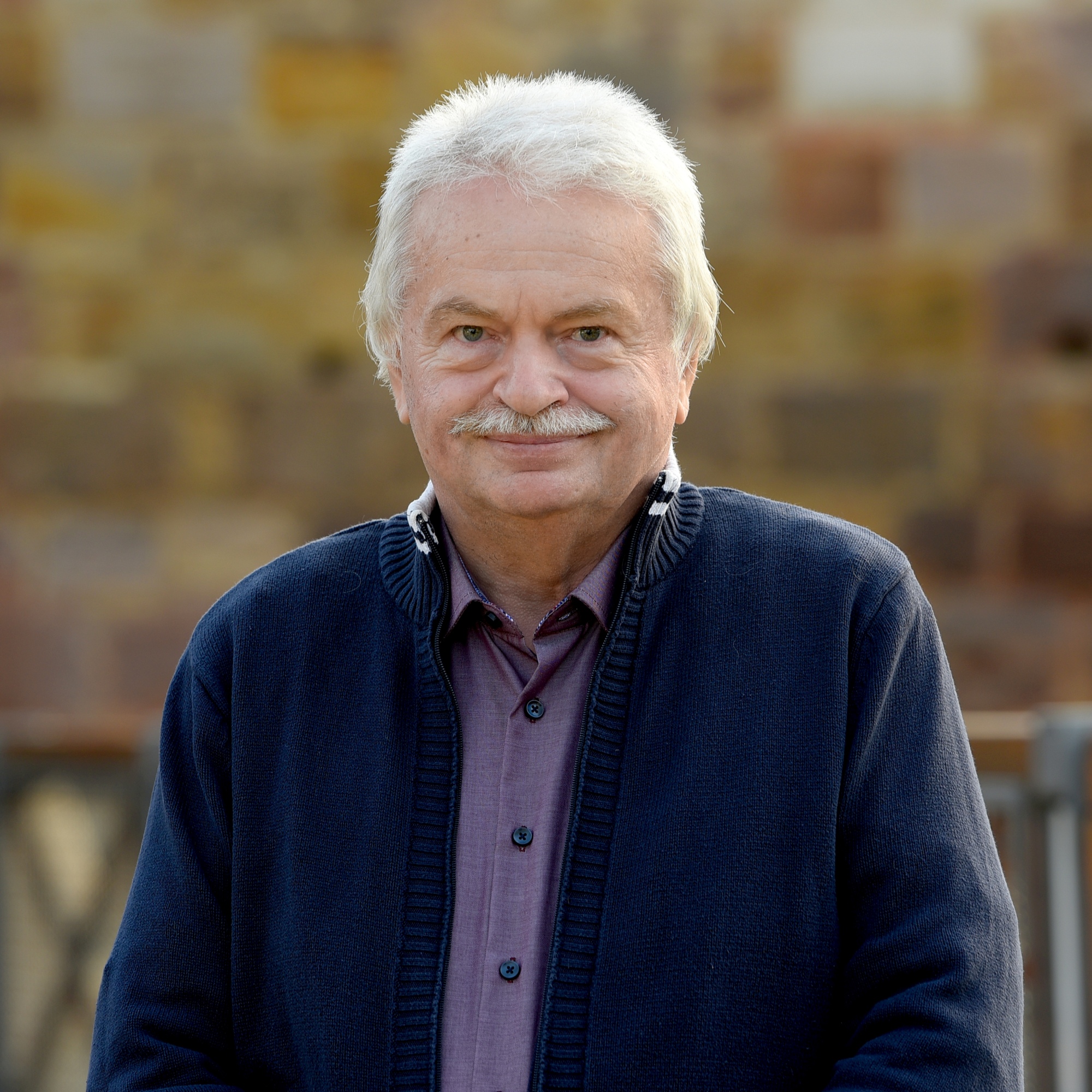 Brustbild von Arthur Reiter, bekleidet mit mit blauer Strickjacke. Kurze graue Haare, Oberlippenbart.