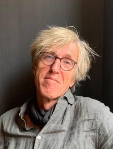 Portrait von Jochen Lendle, leger, Halstuch, offener Hemdkragen, Kopf zur Seite geneigt, lächelt in die Kamera